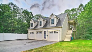 A two-story house with a garage, a covered porch, and a fenced backyard. - Cape Cod Home w/ Deck ~ 3 Mi to Beaches (Buzzards Bay)