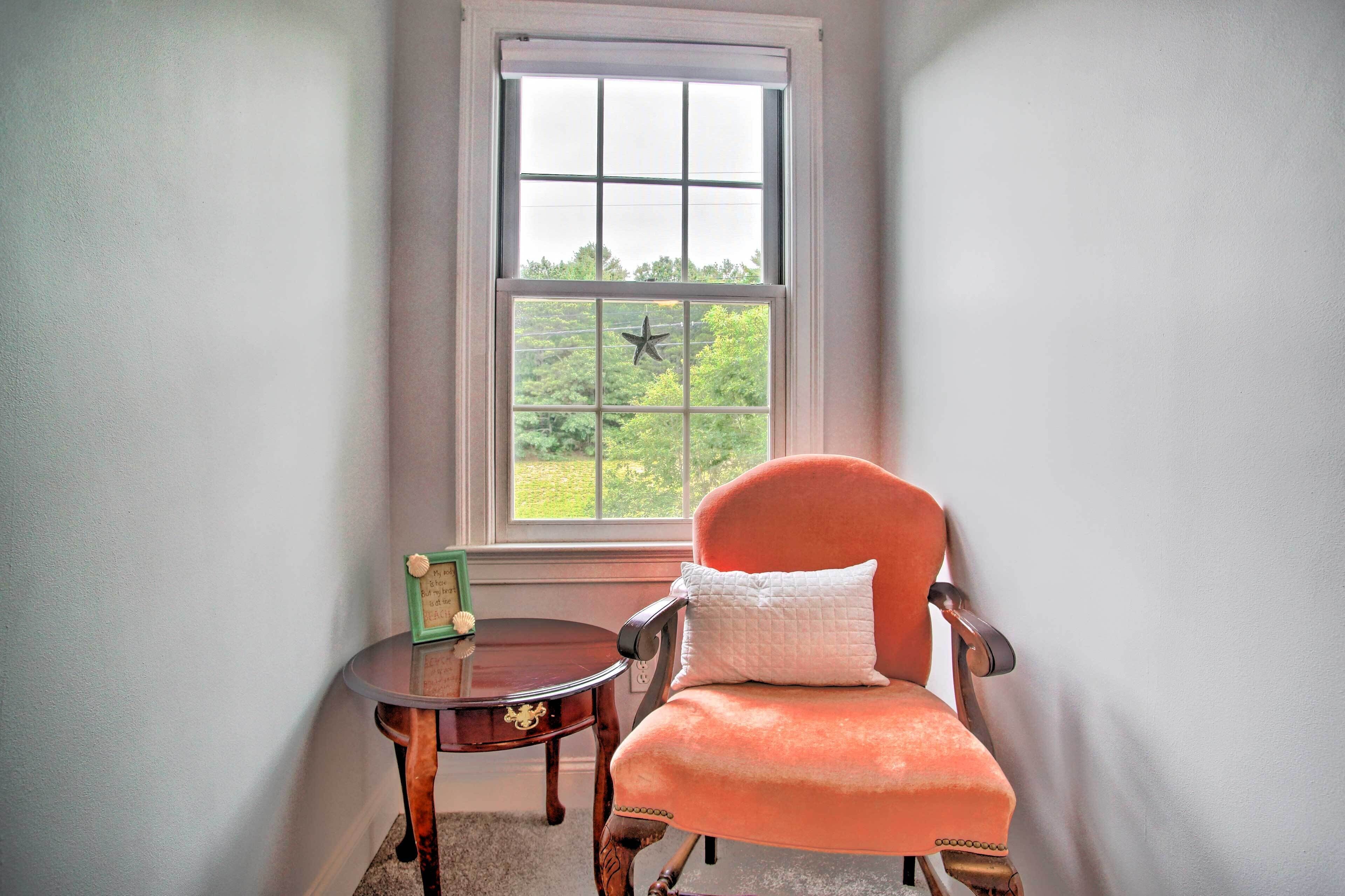 Una habitación de esquina con ventana, una silla y una mesita.