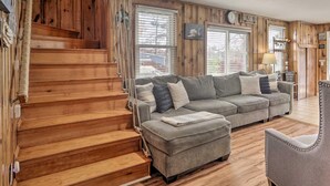 Una escalera de madera conduce a una sala de estar con un sofá gris y un sillón.