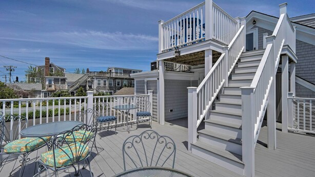 Une terrasse avec des sièges extérieurs, un escalier et une vue sur les maisons voisines.