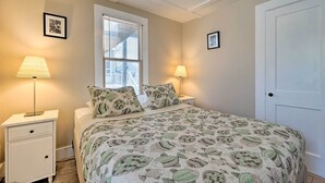 Une chambre à coucher avec un lit, deux lampes de chevet, une fenêtre avec des stores et une porte.