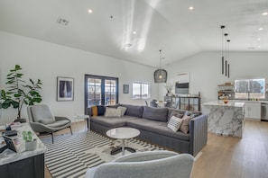 A modern living room with a grey sofa, a round coffee table, and a large plant.