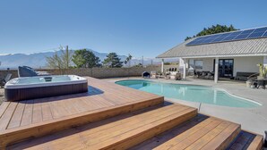 Um quintal com deck de madeira, banheira de hidromassagem e piscina.