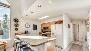 Una cocina moderna con una isla central, taburetes de madera y un amplio ventanal que proporciona luz natural.