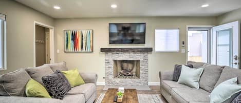 A living room with two sofas, a coffee table, a fireplace, and a TV mounted above it.