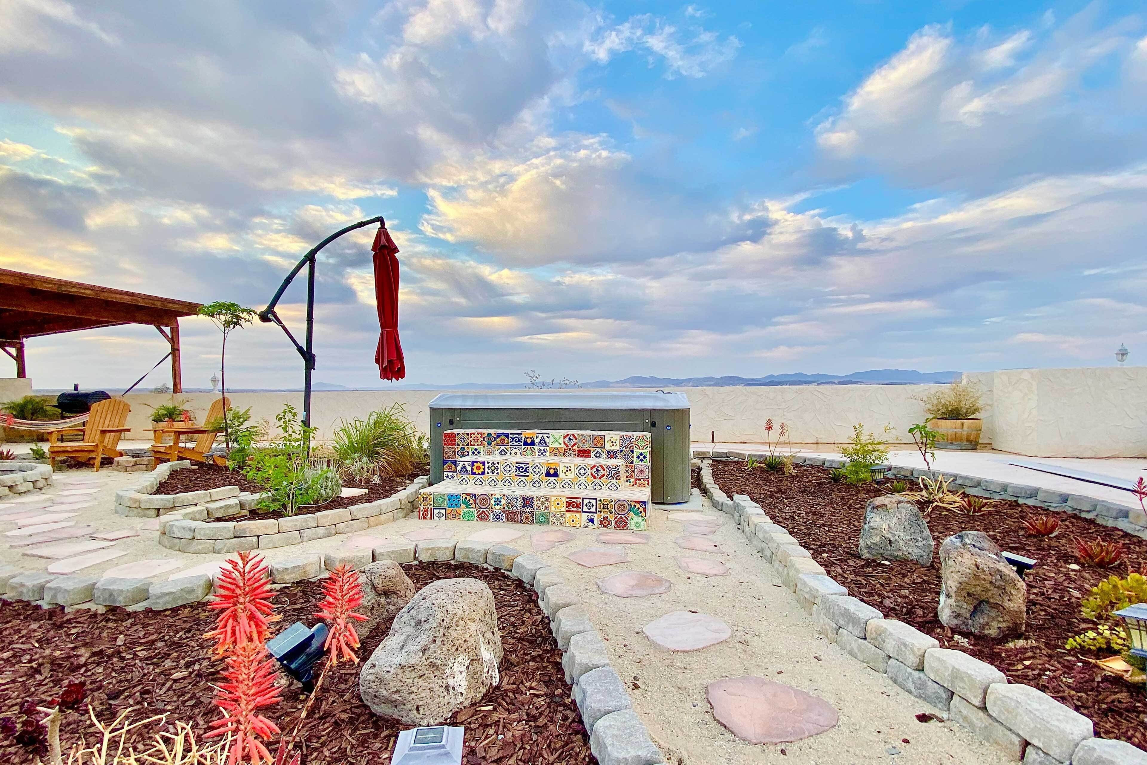 A patio area with a wooden pergola, outdoor seating, a colorful mosaic bench, and a view of the mountains.