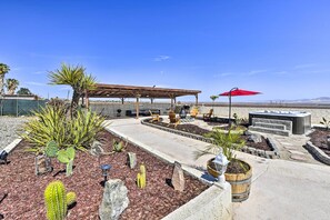 A patio area with a pergola, outdoor seating, and a hot tub.