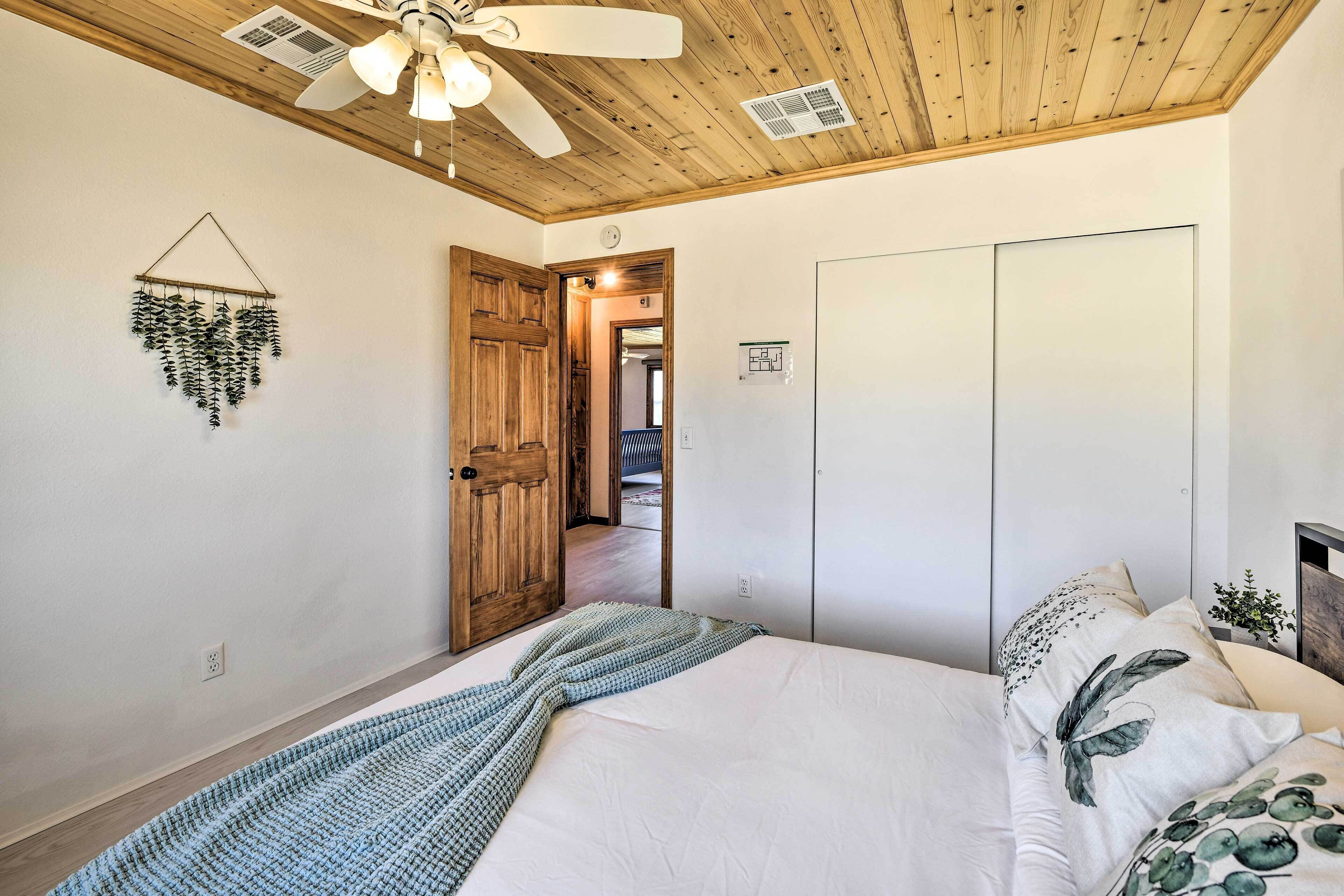 A bedroom with a bed, a ceiling fan, a wooden door, and a white wardrobe.