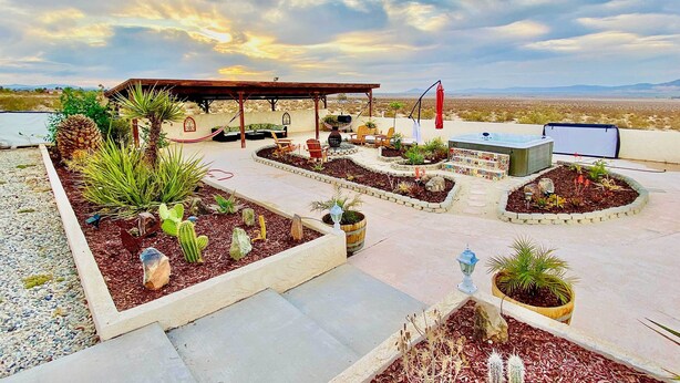 A rooftop patio with a covered seating area, planters with cacti, and a hot tub. - Chic Joshua Tree Pad w/ Mountain Views & Hot Tub (Twentynine Palms)