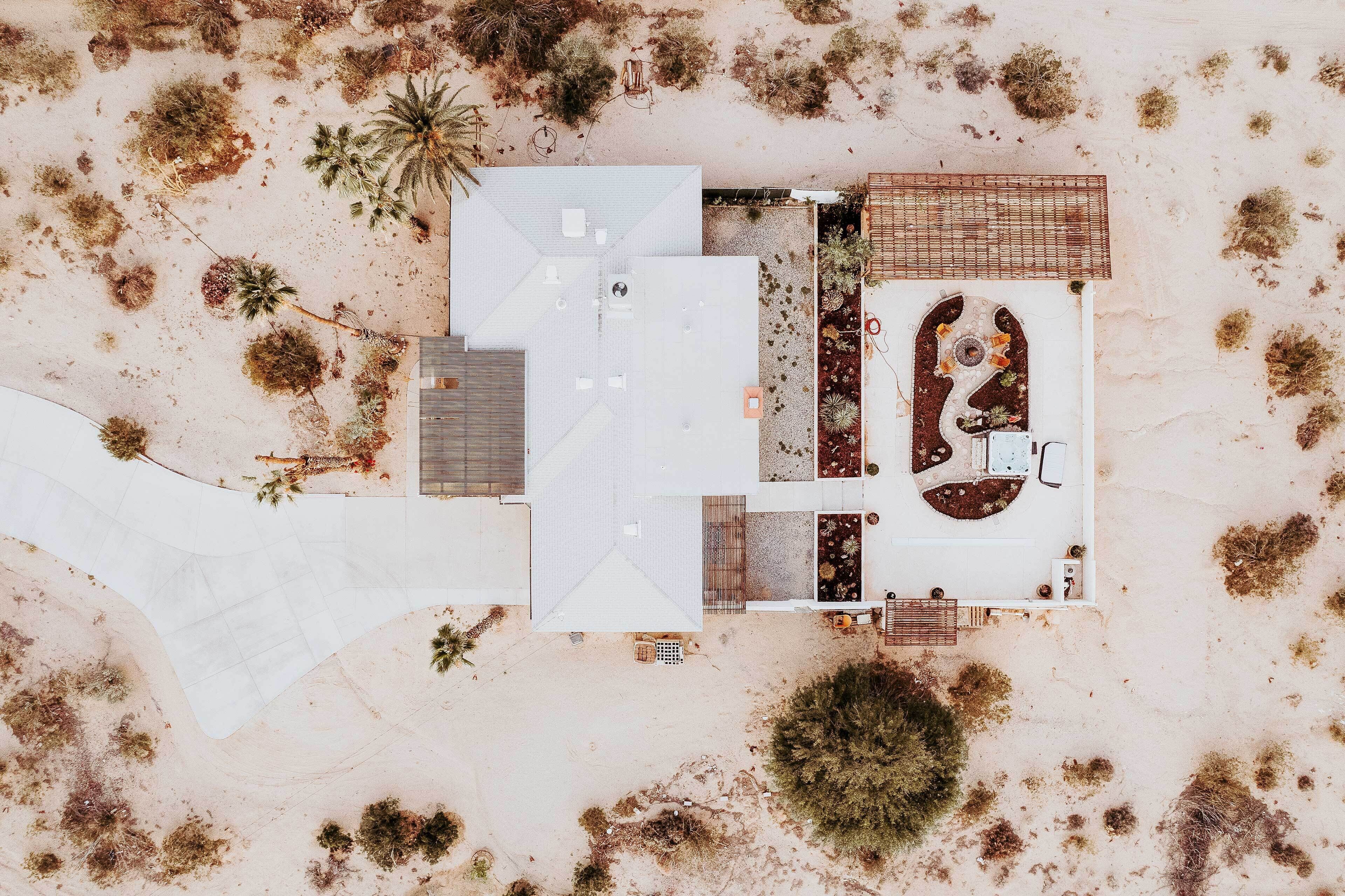 Luchtbeeld van een modern huis met een ruim terras, een zwembad en omliggende beplanting.