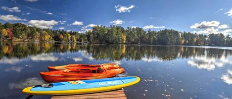 A calm lake with kayaks on a wooden dock.