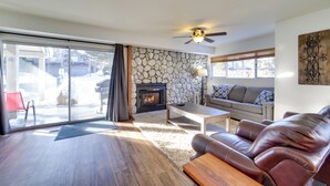 Ein geräumiges Wohnzimmer mit Kamin aus Stein, einer Ledersofa und einer großen Schiebetür zu einer Terrasse.