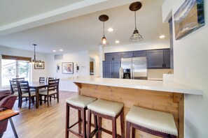 A modern kitchen with a large island, wooden bar stools, and pendant lighting. - Snowcreek Resort Condo w/ Deck at Mammoth Mountain (Mammoth Lakes)