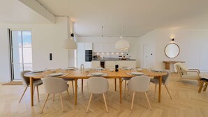 A modern dining area with a wooden table set for six, surrounded by six chairs. - Luxury villa with swimming pool for 8 people (LA COUARDE SUR MER)