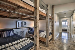 A bunk bed room with a wooden ceiling and metal railings. There are two beds with different bedding styles.