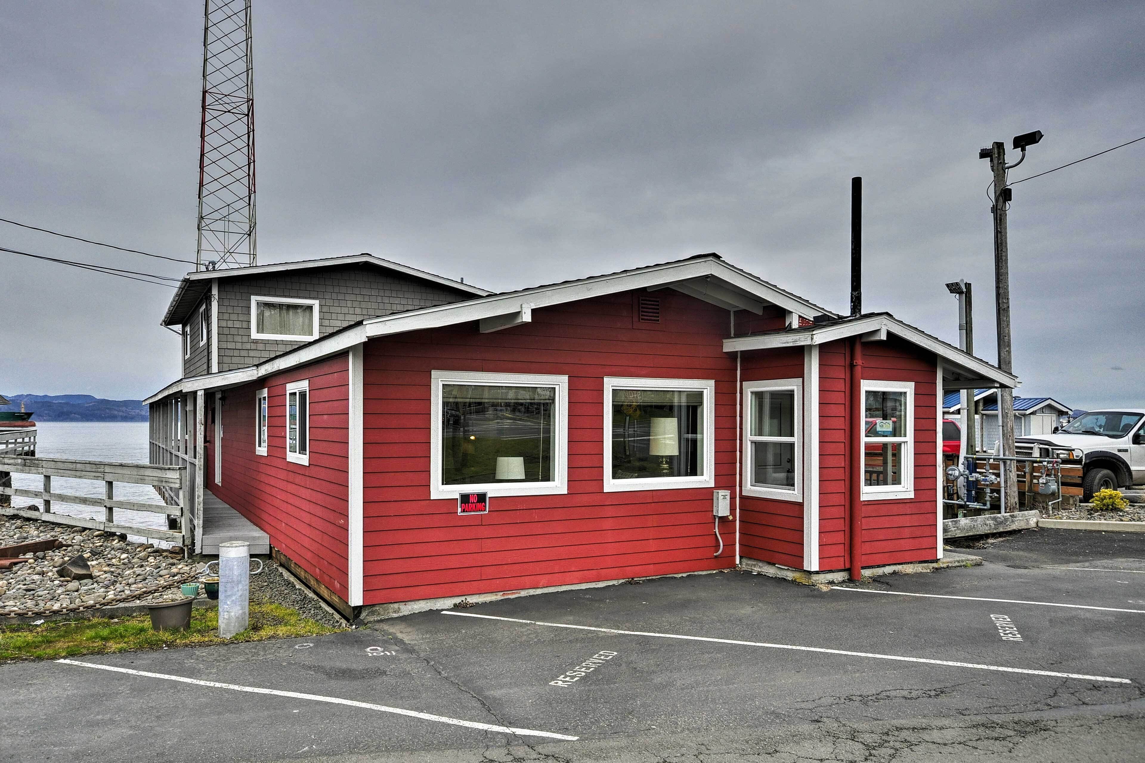 A red building with a dock, a no parking sign, and a parking lot with reserved spaces.
