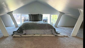 A bedroom with a bed under a sloped ceiling, large windows, and a view of the outdoors. - Private Getaway With All the Amenities (Anderson)