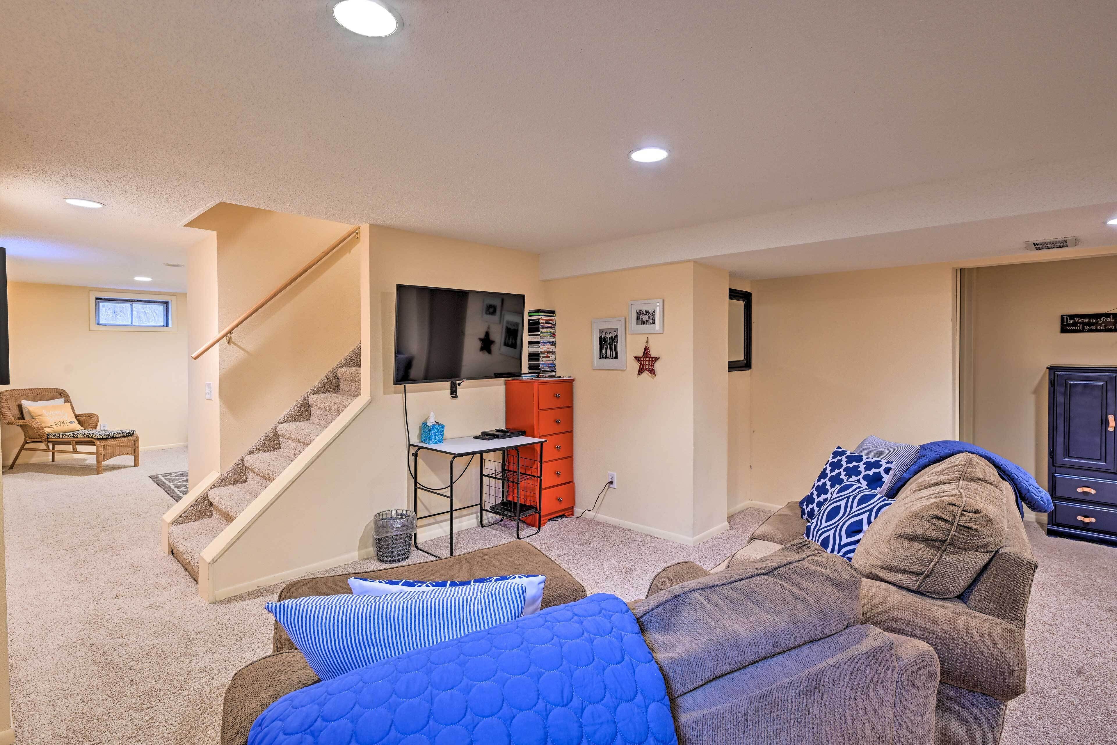 Un salon avec un escalier, un téléviseur fixé au mur, un canapé et une table basse.