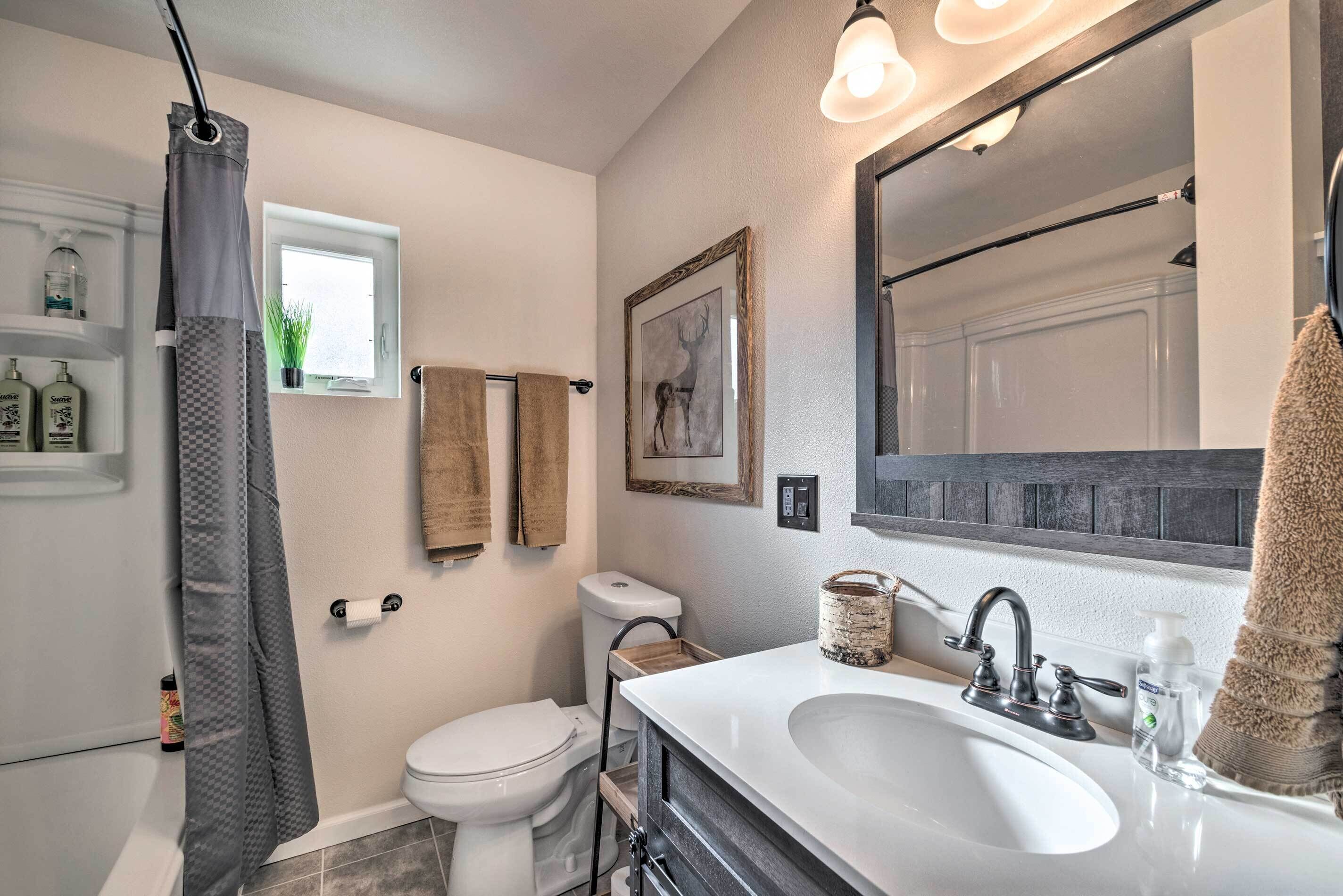 A bathroom with a white sink, a large mirror, a toilet, and a shower curtain.