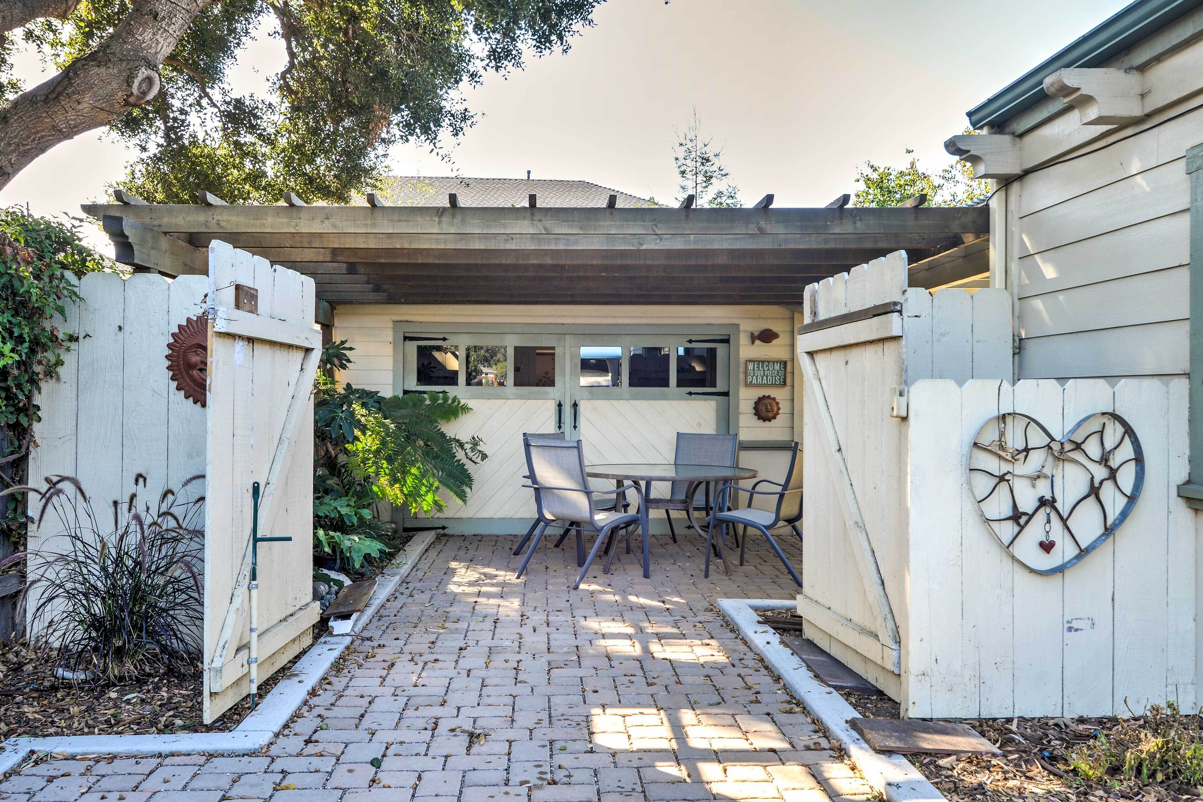 Une terrasse avec une table et des chaises, une pergola et un décor en forme de cœur sur le mur.