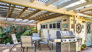 Un patio exterior con una parrilla, sillas y una mesa.