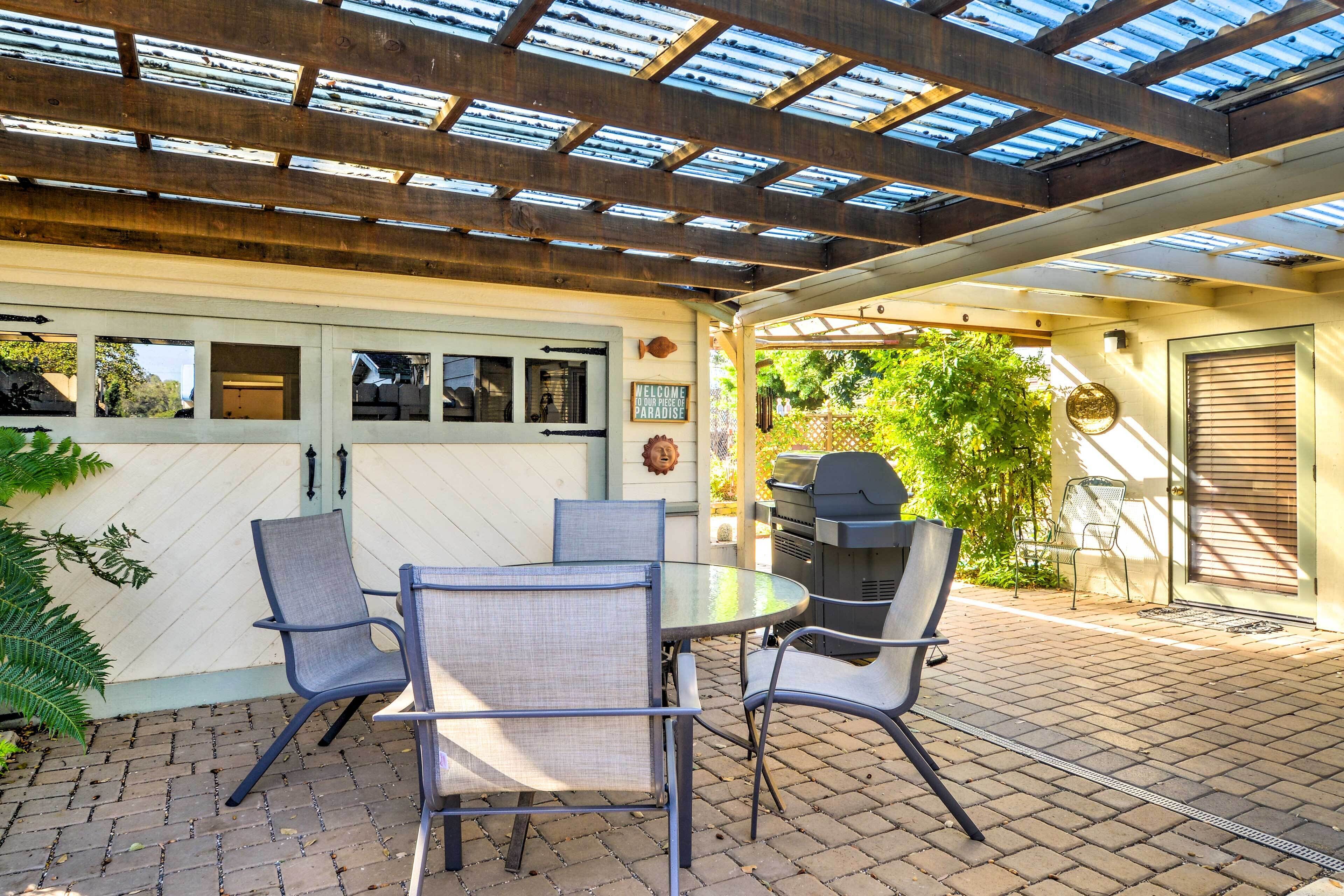 Une terrasse couverte avec une table ronde et des chaises, un barbecue et une porte de garage.