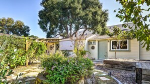 Propiedad residencial con jardín que incluye jardineras de piedra, una pérgola y un árbol grande.