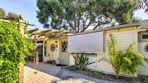 Una casa con una pérgola, un garaje y un jardín con diversas plantas.