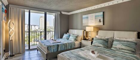 Habitació d'hotel amb dos llits, un balcó i vista a la ciutat, amb un estil de decoració modern.