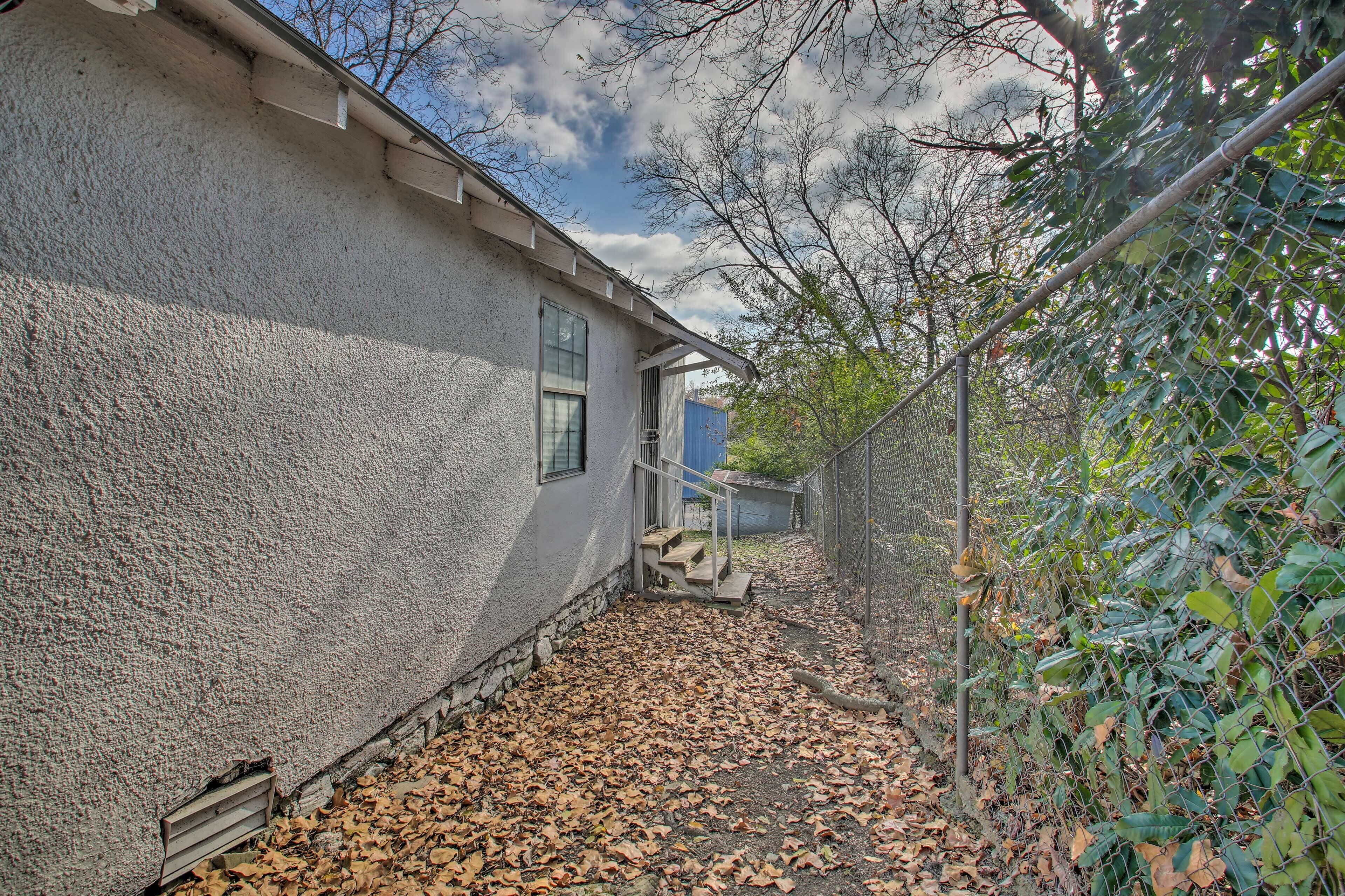 Une maison à l’extérieur texturé, avec une fenêtre bien visible et un espace extérieur abrité, accessible par des marches menant à une porte.