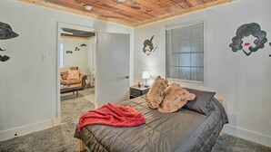 A bedroom with a wooden ceiling, a bed with a red blanket, and wall decorations including a horse and a woman's face. - Hot Springs Home: 2 Mi to Hot Springs Nat'l Park (Hot Springs)