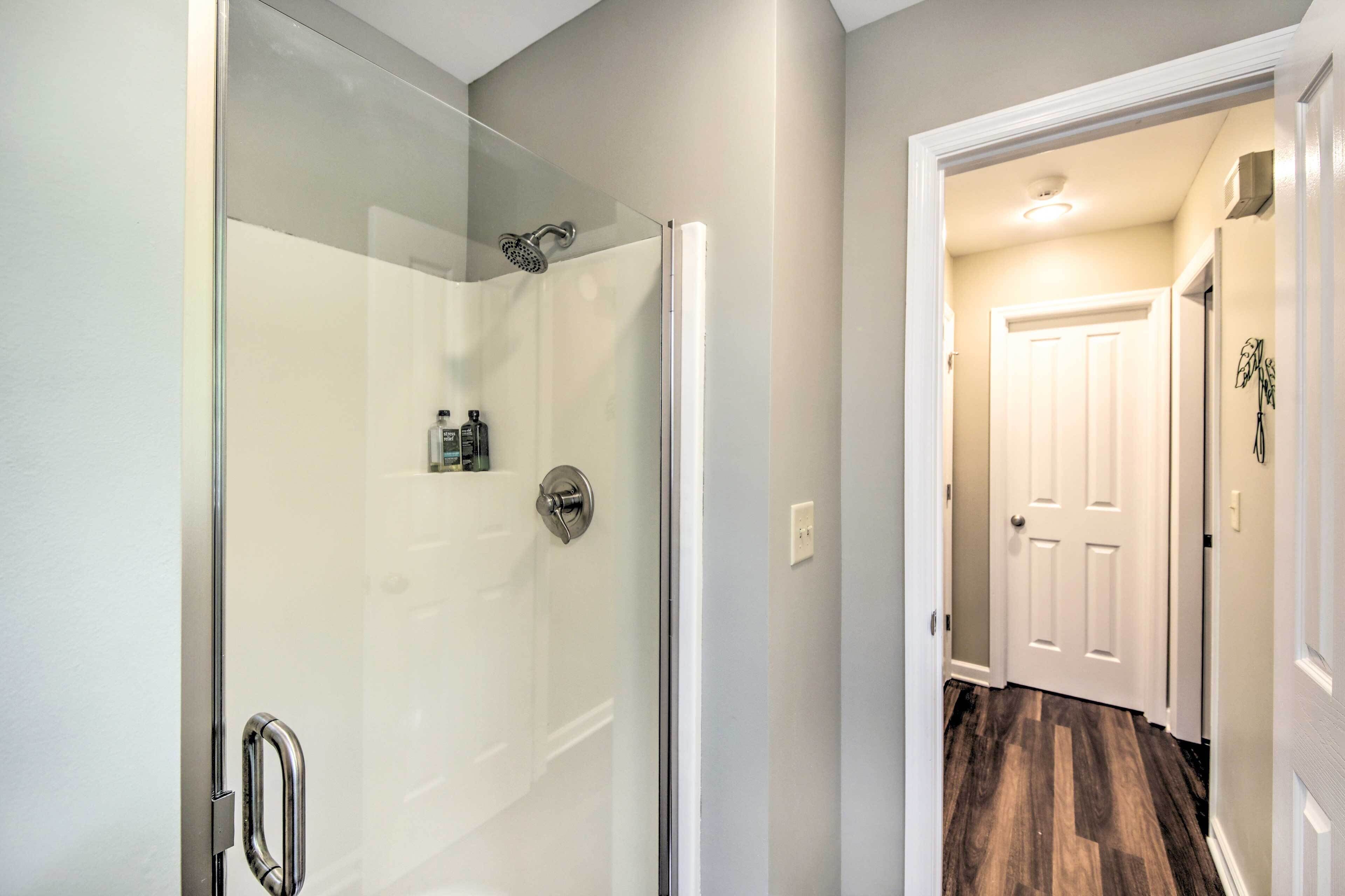 Une salle de bain moderne avec une douche à parois de verre, une porte blanche et un plancher en bois.