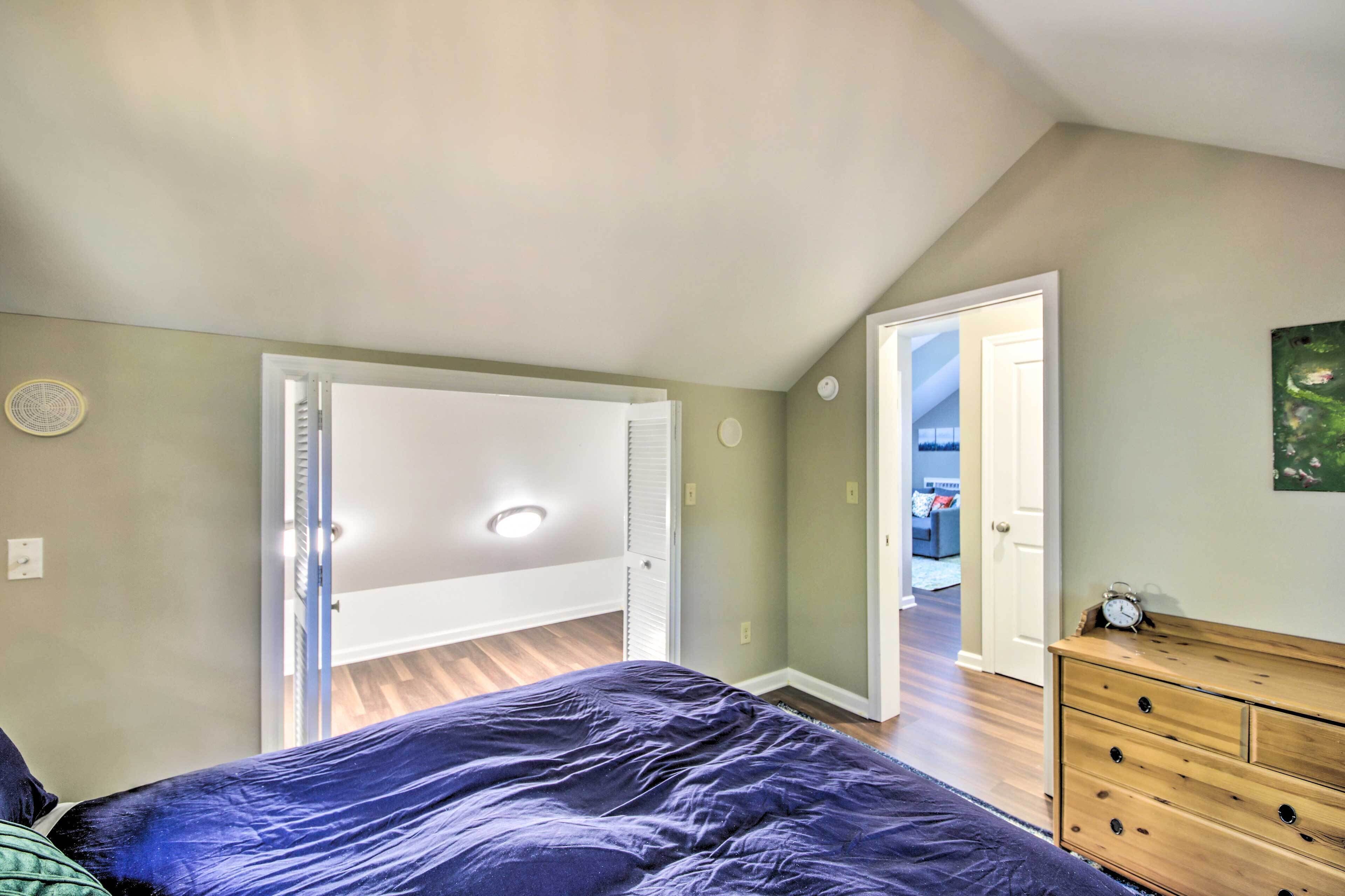 A bedroom with a bed, a dresser, and a door leading to another room.