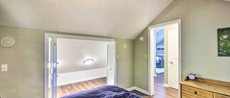A bedroom with a bed, a dresser, and a door leading to another room.