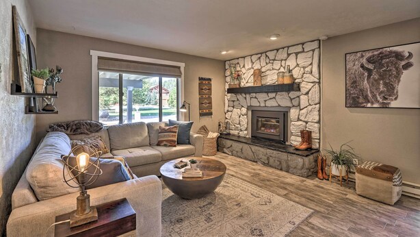 A cozy living room with a stone fireplace, a large window, and a comfortable sofa. - 2 Mi to Rocky Mtn Nat'l Park: Grand Lake Condo (Grand Lake)