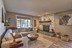 Una sala de estar acogedora con chimenea de piedra, un ventanal grande y un sofá confortable.