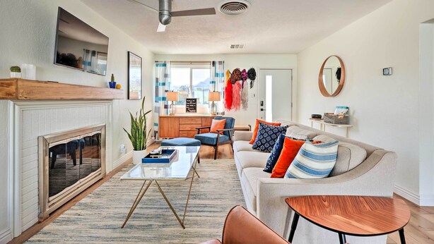 A modern living room with a fireplace, sofa, coffee table, and a view of the kitchen. - < 4 Mi to Dtwn Palm Springs: Home w/ Private Patio (Palm Springs)