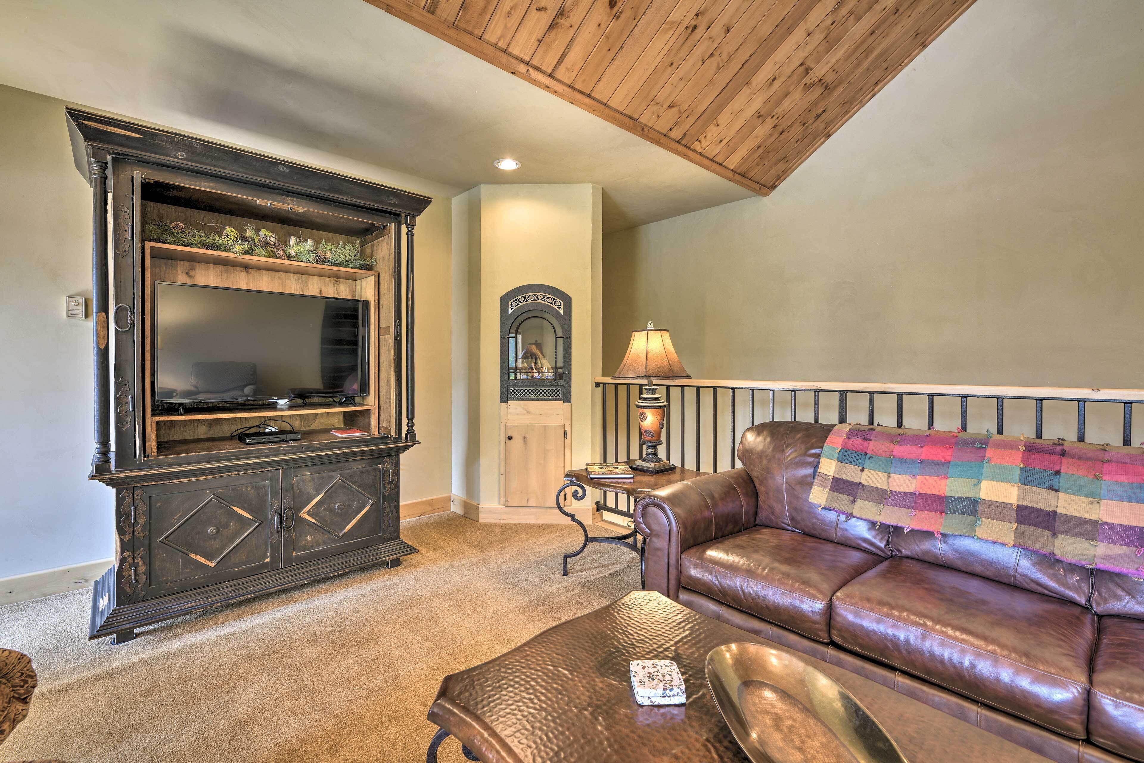 A living room with a dark wooden entertainment center, a leather sofa, and a small table with a lamp.
