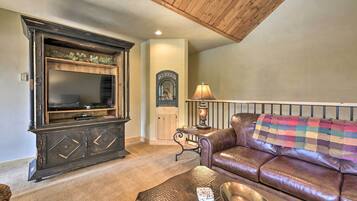 A living room with a dark wooden entertainment center, a leather sofa, and a small table with a lamp.