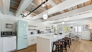 Une cuisine moderne dotée d’un grand îlot central, de meubles blancs et d’un plancher en bois.