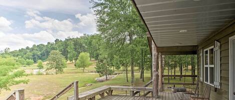 A wooden deck with a view of a golf course and trees.