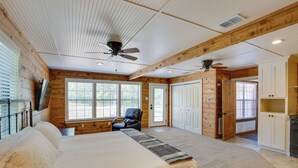 A spacious bedroom with a large bed, a ceiling fan, and a view of the outside through large windows. - Angler's Cabin: Direct Lake Fork Access, By Marina (Alba)