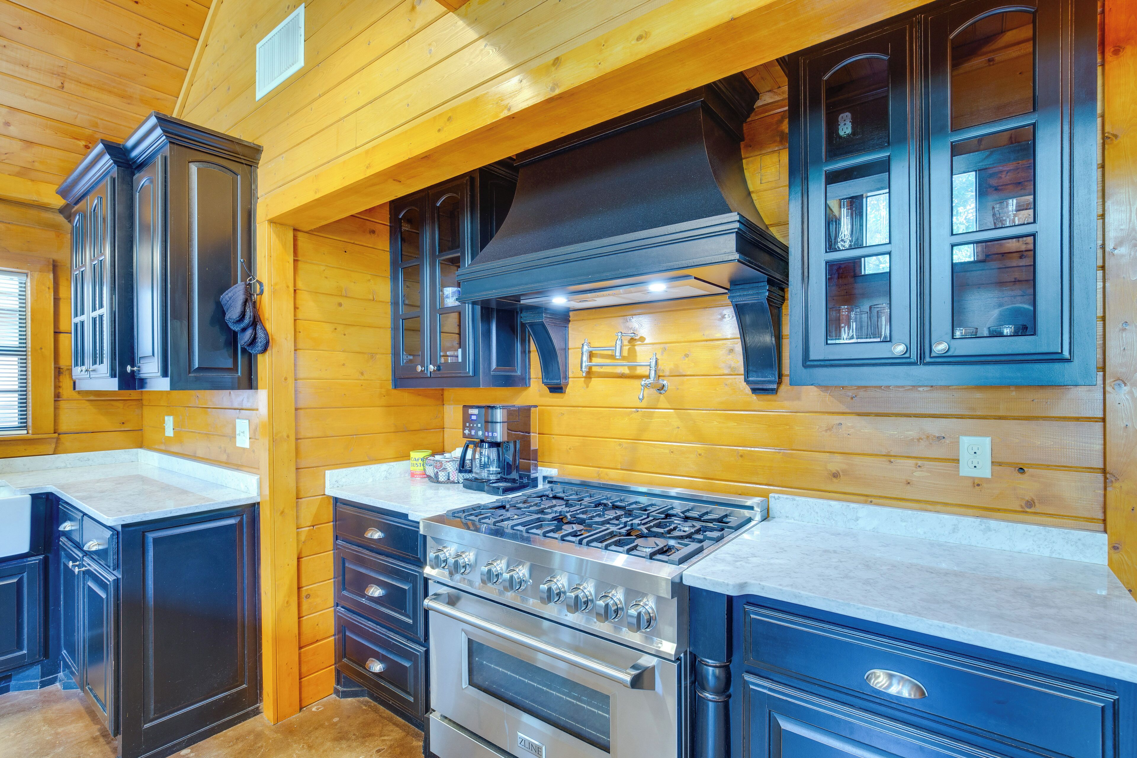 A modern kitchen with wooden walls, a stainless steel stove, and dark cabinetry.