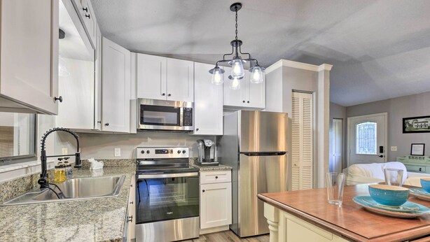 A modern kitchen with white cabinets, stainless steel appliances, granite countertops, and a wooden island. - Charming Ocala Home Near World Equestrian Center! (Ocala)