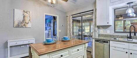A kitchen with white cabinetry, a wooden countertop, a ceiling fan, and a dishwasher.