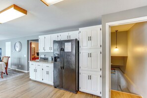 A modern kitchen with white cabinets, a stainless steel refrigerator, and a dining area with a table and chairs. - 2 Decks, Lake Views! Group Escape in Osage Beach (Osage Beach)