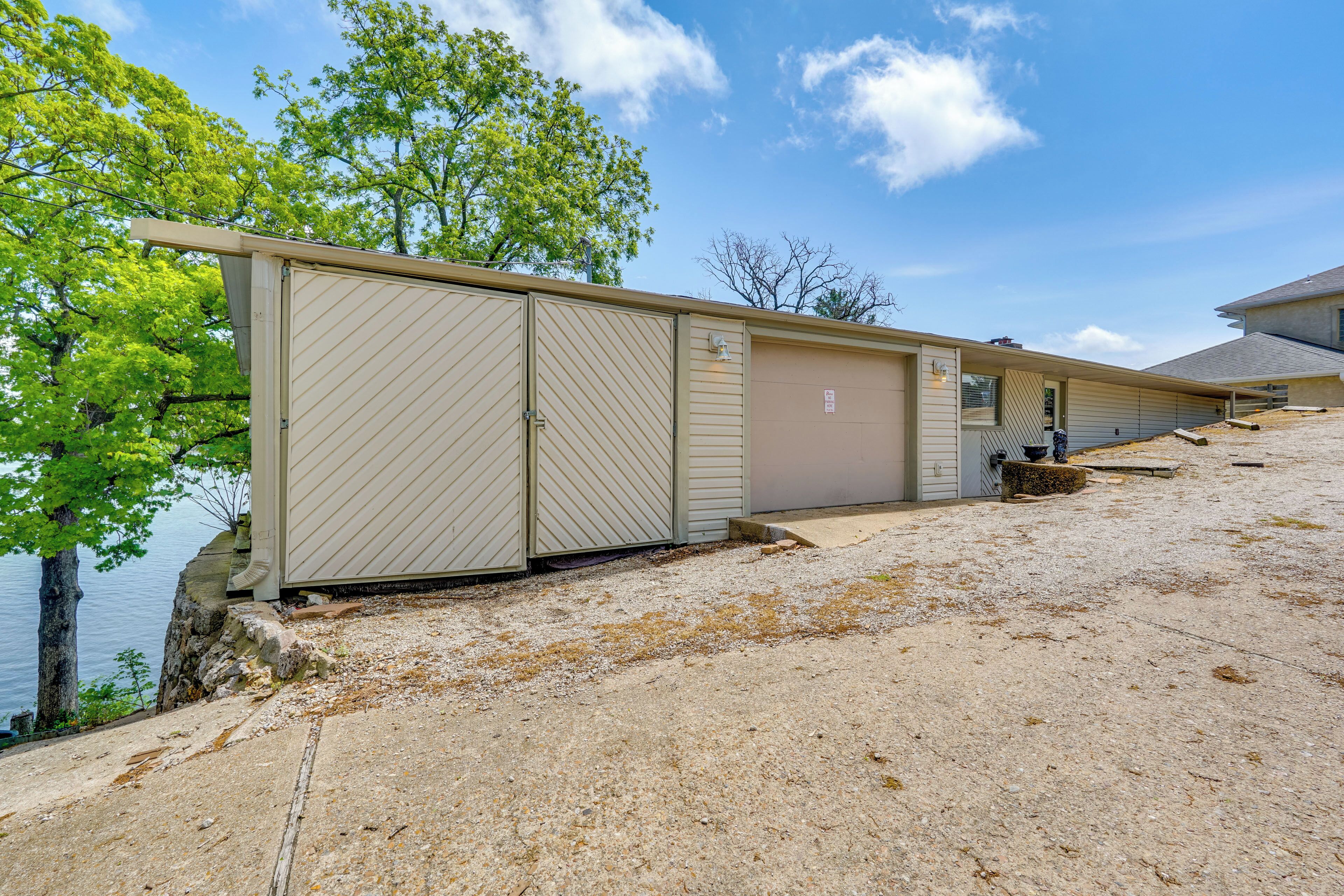A row of beige mobile homes with a gravel driveway and a body of water in the background.