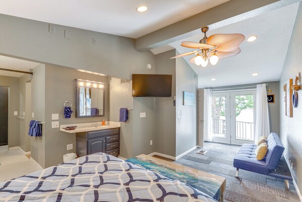 A bedroom with a bed, a vanity with a mirror and lights, a ceiling fan, and a view to the outside. - 2 Decks, Lake Views! Group Escape in Osage Beach (Osage Beach)