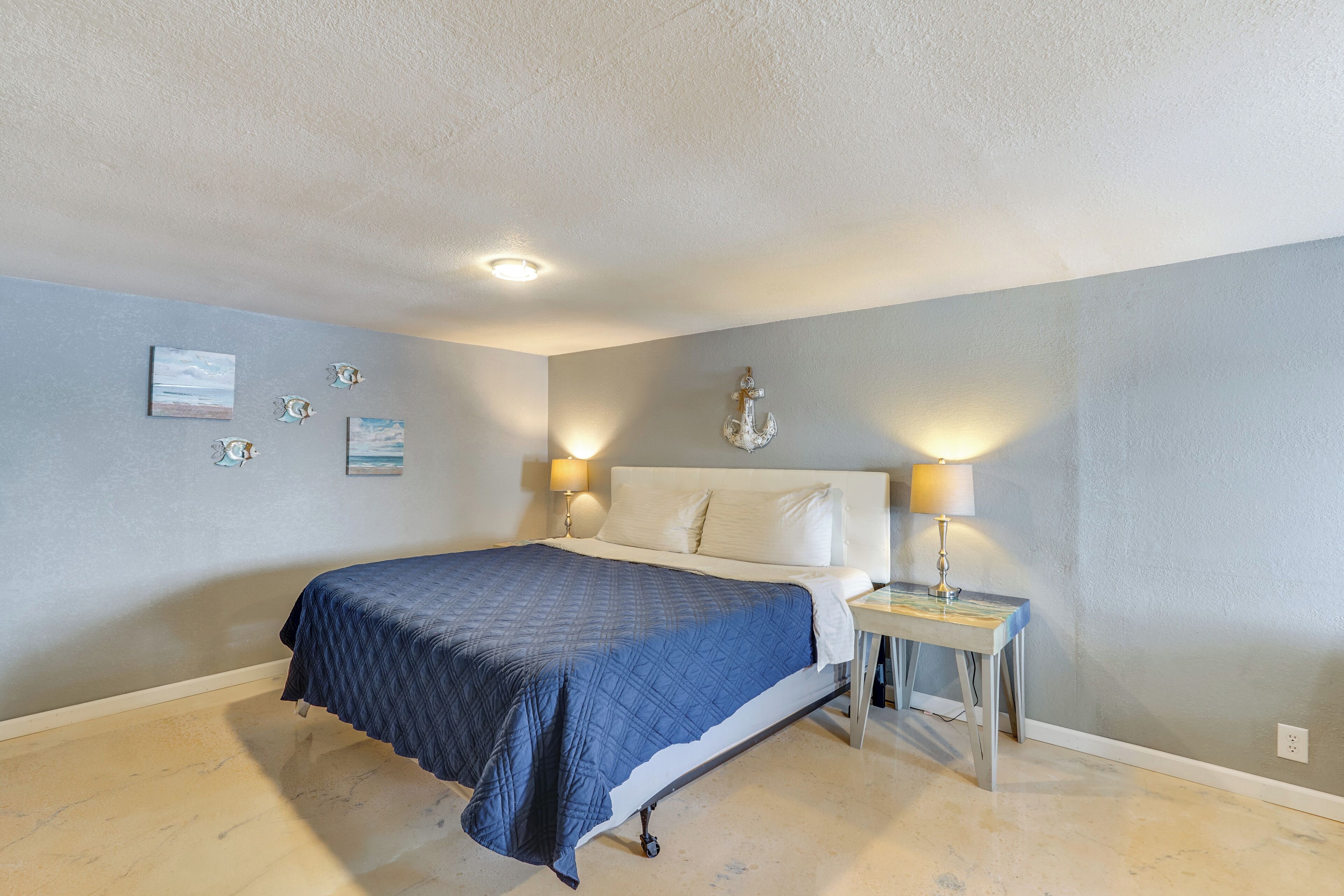 Un dormitorio con cama, lámparas de noche y decoración en la pared.