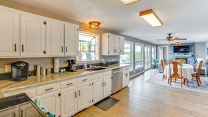 Una cocina moderna con armarios blancos, una isla grande y un comedor con sillas y una mesa de madera.